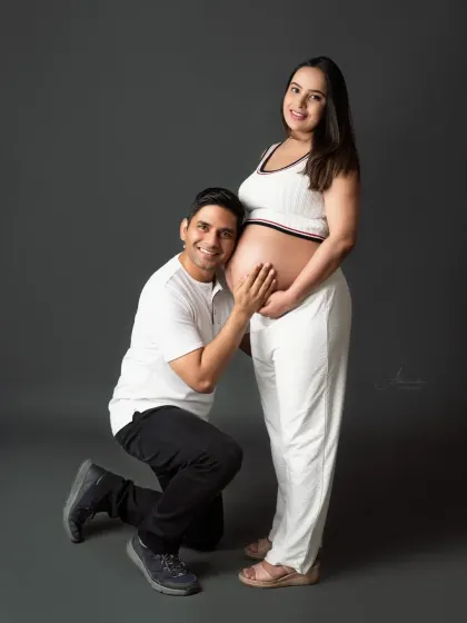 A joyful and loving moment. The dad-to-be smiles brightly as he kneels to listen to the baby, sharing his excitement.