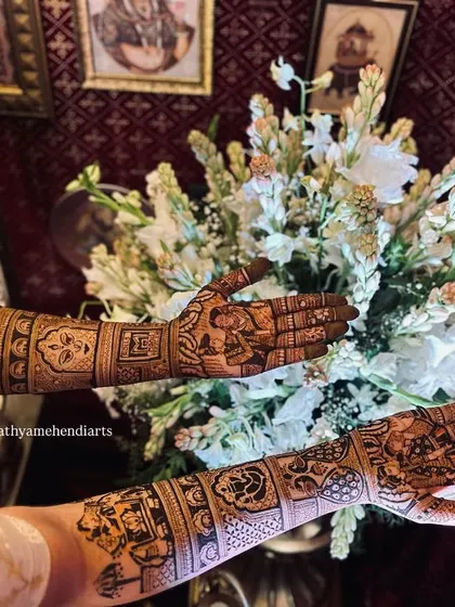 Another beautiful view of the bride's hands over the floral arrangement, giving a clear look at the detailed figures and patterns on both arms.