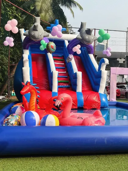 An inflatable pool complete with a slide, a pink flamingo float, and other fun pool toys.