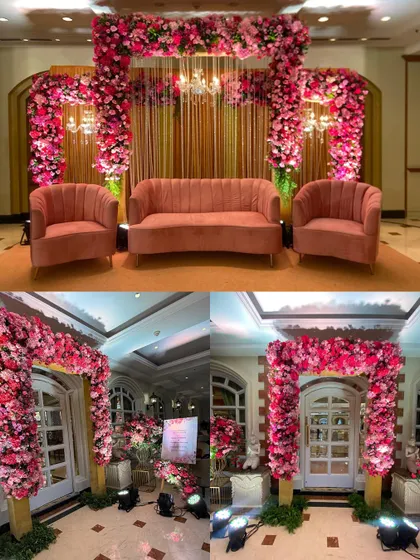 A cohesive decor theme showing a lush pink floral stage with matching velvet seating, paired with a beautiful floral archway at the entrance for a Roka ceremony.