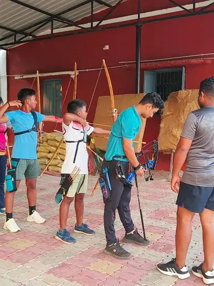 A coach provides guidance to a young archer. One on one attention and expert feedback are crucial for technical sports like archery.