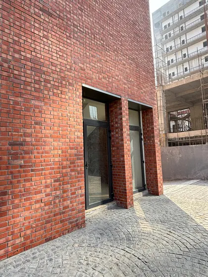 A ground-level detail of an exposed brick exterior with inset doorways. The cobblestone paving complements the texture of the walls, demonstrating our focus on creating a cohesive material experience from the ground up.