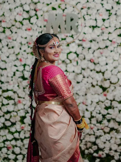 A beautiful shot of the bride looking back over her shoulder, showcasing her traditional hairstyle and saree against a floral backdrop.