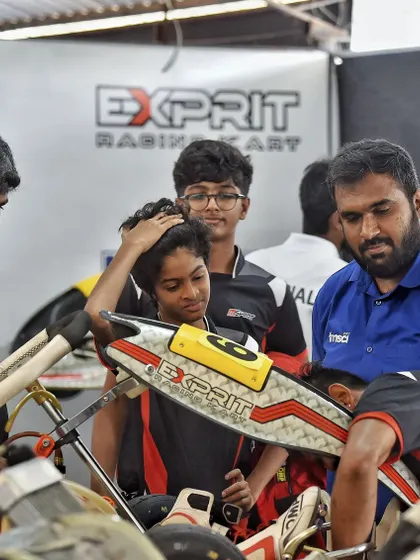 A young driver receives guidance in the pits. We foster a learning environment where experienced mechanics and coaches support emerging talent.