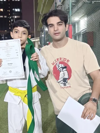 A student receives his green belt after passing his grading exam. His dedication is an example to others.