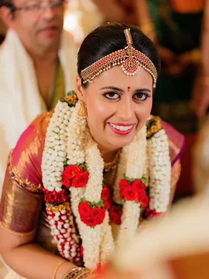 A close-up of her radiant smile, with a bold red lip that adds a touch of classic bridal glamour.