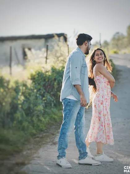 A candid shot of a couple walking along a country road. The woman's backward glance and smile create a lovely, spontaneous moment that feels authentic and full of joy.