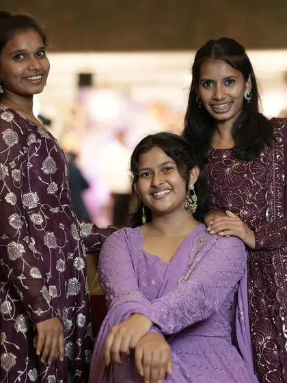 A group portrait of three young women in coordinating outfits at a family gathering.