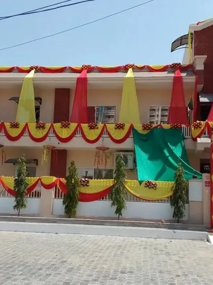 A wedding house decorated with yellow and red drapes across two floors, creating a traditional and festive appearance.