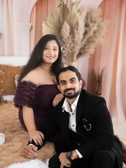 A formal and elegant couple's portrait. The dad-to-be looks lovingly at his partner, who is seated in our boho bedroom setup.