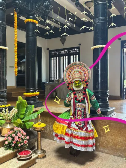 The vibrant colors of the Kathakali costume are highlighted with a bright pink squiggle and some sparkles.