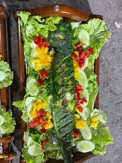 For seafood lovers, I offer special platters like this whole grilled fish, marinated in a green herb masala and garnished with fresh vegetables. It's a healthy and delicious option for any party.