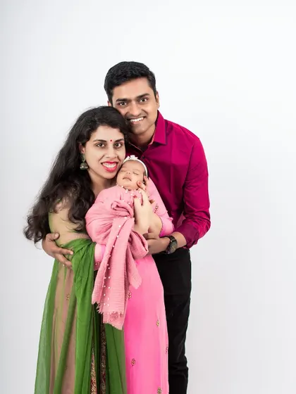 A beautiful studio portrait of a new family. The parents' colorful outfits contrast beautifully with the simple white background, creating a vibrant image.