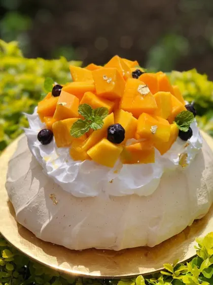A large mango pavlova, perfect for sharing. It's a showstopper dessert for any summer gathering.