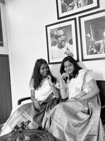 A black and white photo with a friend, capturing a retro, nostalgic feel. We were dressed in sarees, surrounded by portraits of musical legends.