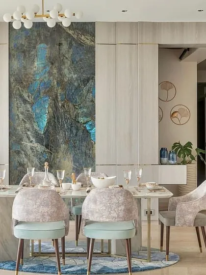 This dining area makes a bold statement with a large, blue-toned marble slab as a feature wall. The design is balanced with neutral-toned chairs and a simple, modern dining table.