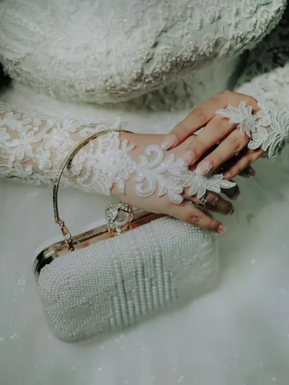A detail shot of the bride's accessories, including her elegant pearl clutch and delicate lace gloves.