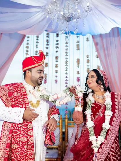 The playful Varmala exchange under a beautiful mandap with a chandelier, overlooking the sea.