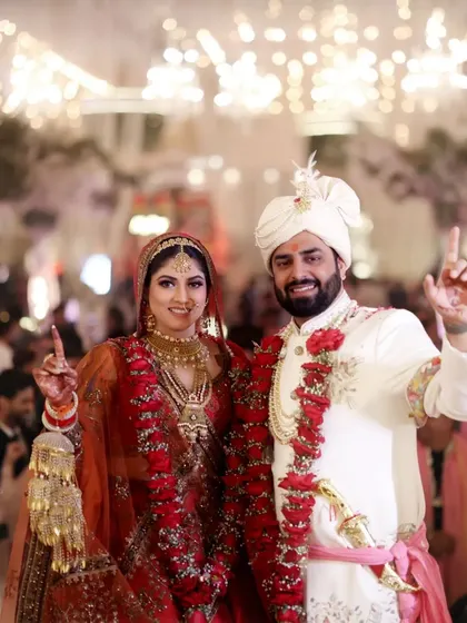 A celebratory shot of the couple after their wedding, pointing to the sky in triumph.
