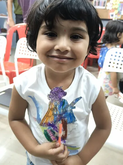 The joy on this little girl's face says it all. She has just finished coloring her own puppet after watching the Chitrakathi show, a perfect hands-on activity to make the cultural experience even more memorable.