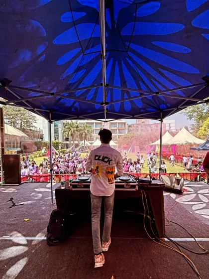 Another perspective of the massive UCB Holi event, showing the huge outdoor setup under a blue tent.