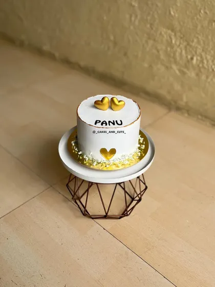 An aesthetic love-themed cake with golden hearts, simple and elegant.