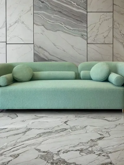 The same 'Cloud' sofa design shown in a refreshing mint green bouclé. The color completely transforms its personality, making it feel light and airy against the marble flooring.