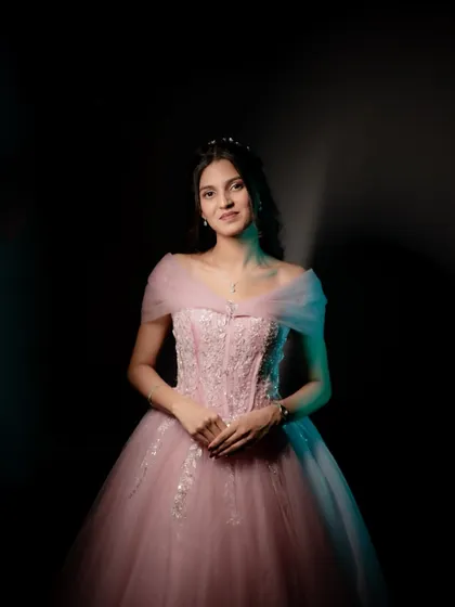 A dramatic portrait of the bride-to-be in a beautiful pink ball gown, using creative lighting to create a moody and elegant feel.
