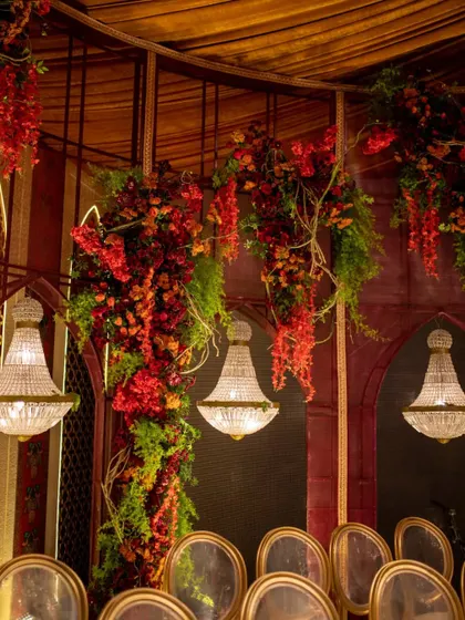 Cascading arrangements of red and green florals adorn the walls, creating a lush and vibrant backdrop for the spiritual gathering.