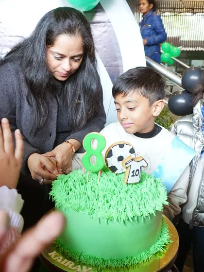 The cake-cutting moment at Kairav's 8th birthday, featuring a green cake designed to look like a football pitch.