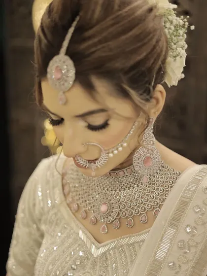 A close-up of the minimalist bride's hair and makeup. The white floral bun and delicate diamond nath complete this modern and sophisticated bridal style.