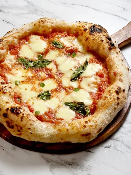 Behold, the queen of pizzas, the Margherita. This isn't just any Margherita, it's a contemporary Neapolitan style, made with authentic San Marzano tomatoes, fresh mozzarella, and basil, all on a perfectly charred, leopard-spotted crust.