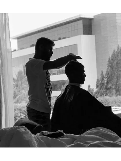 A silhouette shot during a hotel room haircut. No matter the location, the focus is always on delivering a perfect cut.
