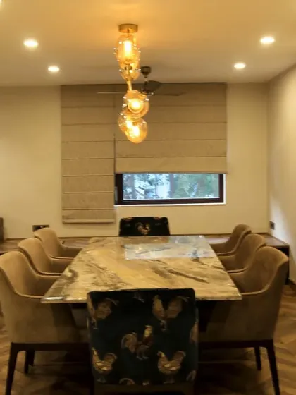A sophisticated dining room with a marble-top table and plush upholstered chairs. The cascading glass chandelier serves as a stunning centerpiece.