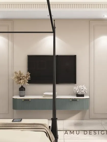 The opposite view of the Indirapuram bedroom concept, showing the minimalist TV console and a comfortable armchair, all set against a wall with elegant, classic paneling.