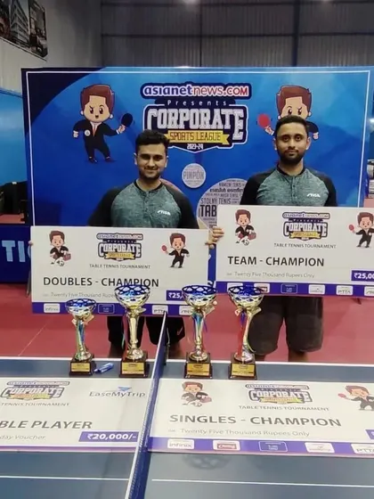 Ashwin H and his partner showcasing their trophies after winning the Doubles and Team Champion titles at the All India Corporate tournament.