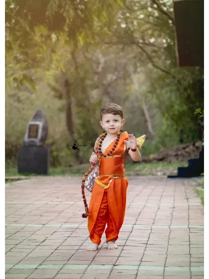 A full-length shot of the little boy walking confidently in his Lord Ram attire during his third birthday outdoor shoot.