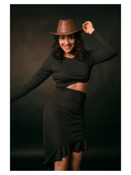 A joyful and energetic portrait of a model in a black dress and cowboy hat. Her expression is full of life and energy.