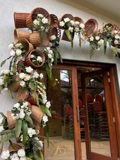 A unique floral entrance piece made from woven baskets and white roses, demonstrating a creative fusion of rustic and elegant styles.