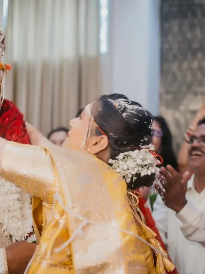 The bride joyfully places the garland on the groom during the varmala ceremony, a moment filled with laughter and applause.