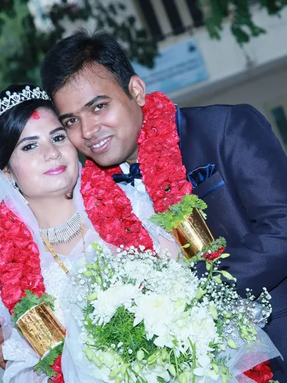 A portrait of a newly married couple, adorned with traditional red garlands.
