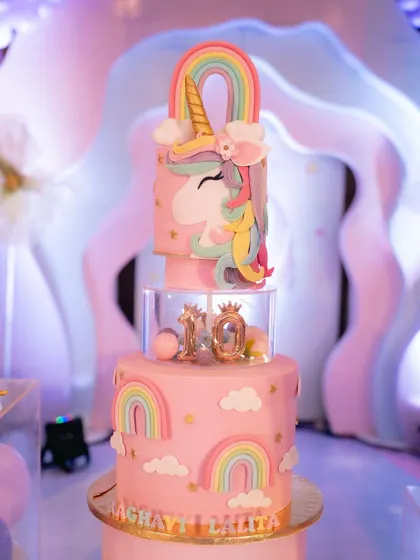 A birthday isn't complete without a cake. This multi-tiered unicorn cake was the centerpiece of the dessert table, surrounded by pastel balloons and rainbow decorations.
