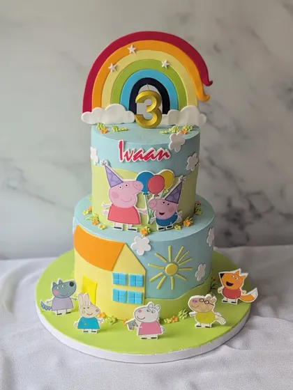A fun-filled Peppa Pig party on a cake! This two-tier creation shows Peppa, George, and their friends playing outside their house under a bright rainbow.