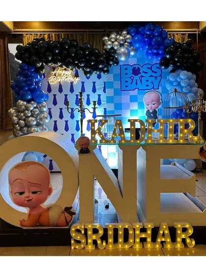 A sharp and fun "Boss Baby" themed first birthday party. The decor uses a blue, black, and silver color scheme with character cutouts, large "ONE" letters, and a custom backdrop for a cool and playful celebration.