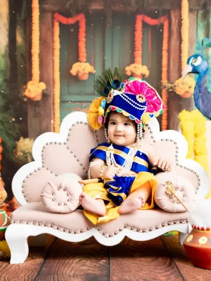 A classic portrait of a baby as little Krishna, sitting confidently on his throne. The lighting highlights his happy expression and colorful costume.