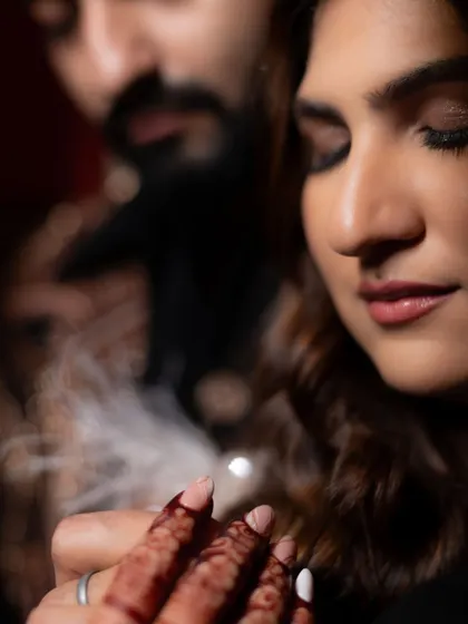 A beautiful, soft-focus shot of the bride's hand on her groom's, with her henna-stained fingers. It’s a small detail that speaks of intimacy and connection amidst the glamour of the cocktail night.