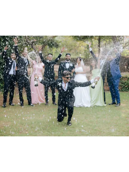 The groomsmen and the couple celebrate with a champagne spray, a perfect shot of pure celebration.