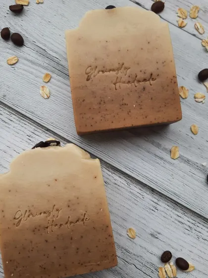 A top-down view of my Scrubby Coffee soap, made with real coffee grounds for exfoliation and creamy oat milk for moisture. I arrange whole coffee beans and oats around the bars to show you the simple, wholesome ingredients inside.