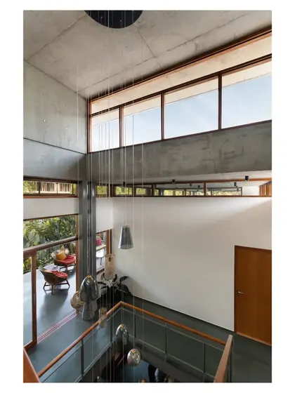 A view from the upper level looking down into the triple-height volume. The large windows and clerestories are strategically placed to flood the home with natural light throughout the day.