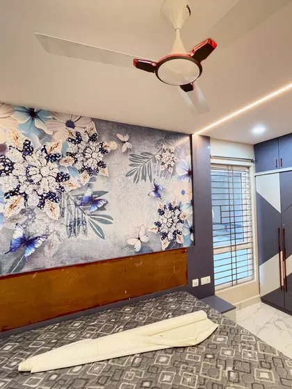 A modern bedroom with a custom wallpaper featuring a blue floral and butterfly design, perfectly complementing the room's grey and white color scheme.